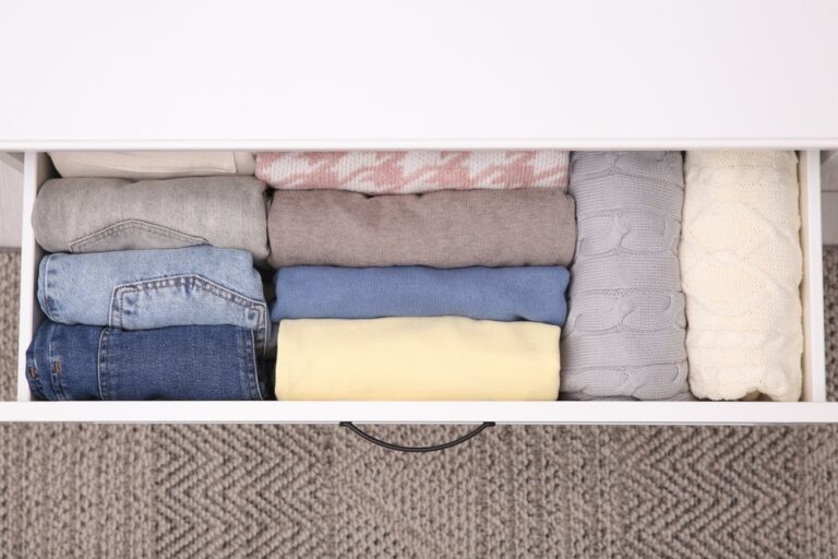 Jackets and other clothes are folded in the drawer.